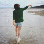 Mulher 49 anos caminhando na praia no fim de tarde.