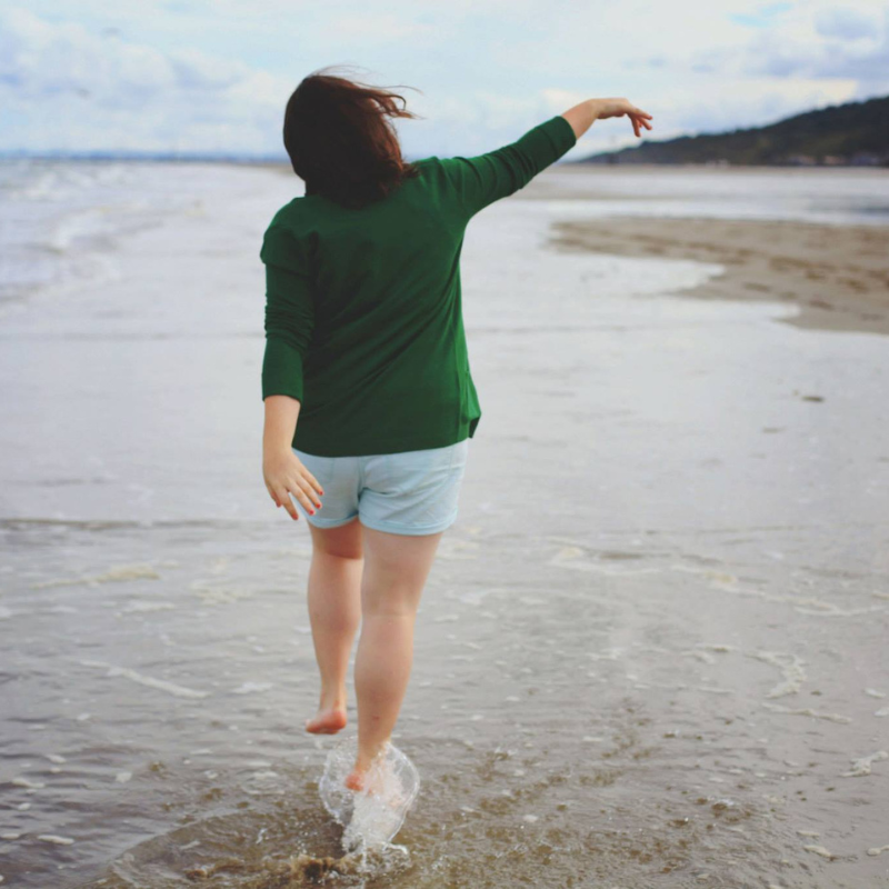 Mulher 49 anos caminhando na praia no fim de tarde.